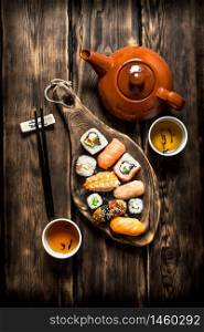 Sushi and rolls with herbal tea. On a wooden table.. Sushi and rolls with herbal tea.