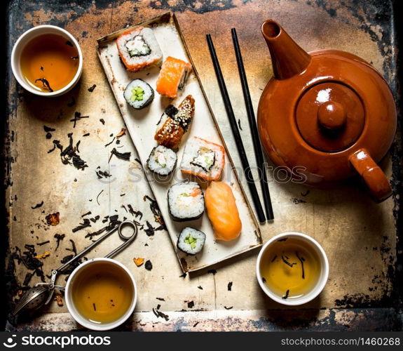 Sushi and rolls with herbal tea on an old rustic background .. Sushi and rolls with herbal tea