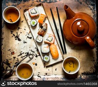 Sushi and rolls with herbal tea on an old rustic background .. Sushi and rolls with herbal tea