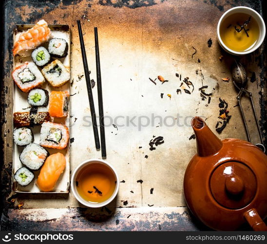 Sushi and rolls with herbal tea on an old rustic background .. Sushi and rolls with herbal tea