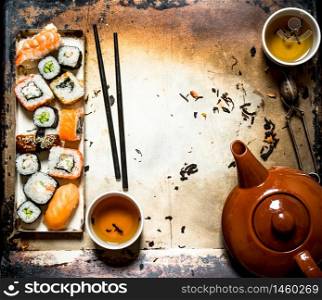 Sushi and rolls with herbal tea on an old rustic background .. Sushi and rolls with herbal tea