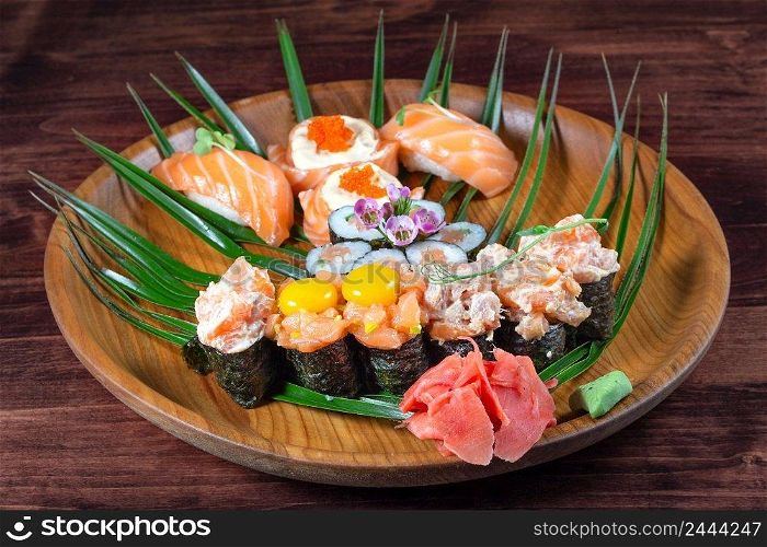 Sushi and rolls with raw quail eggs on a wooden plate with green leaves. Wooden table. Selective focus. Sushi and rolls with raw quail eggs on wooden plate with green leaves