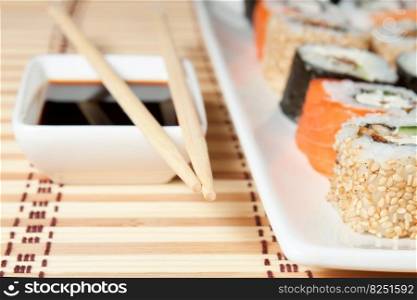 sushi assortment on white plate, with soy sauce over bamboo background.. Sushi Assortment On White Dish over bamboo background.
