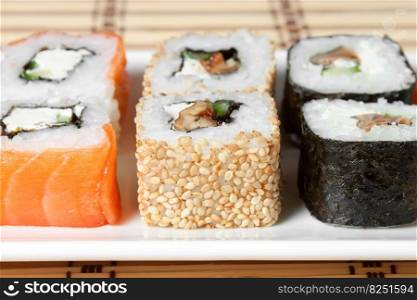 sushi assortment on white plate, with soy sauce over bamboo background.. Sushi Assortment On White Dish over bamboo background.