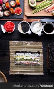 sushi cooking set with rice and ingredients served at black dish at black table. flat lay
