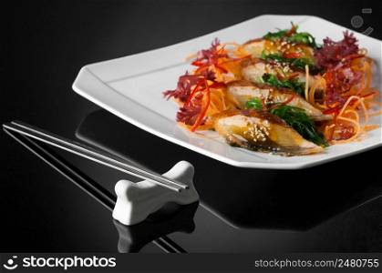 sushi in a white plate with chopsticks on a black background with reflection . sushi in a plate on a black background