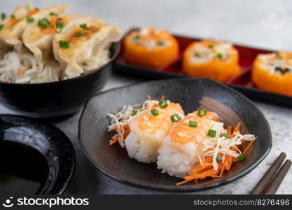 Sushi is in a plate with chopsticks and dipping sauce on a white cement floor.