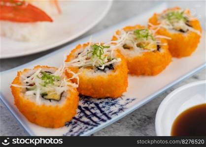 Sushi is on a plate with dipping sauce on a white cement floor.