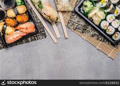 Sushi menu with nigiri, maki and inside rolls, summer rolls in rice paper wrappers on gray on gray stone background, top view, border. Japanese and Asian food.