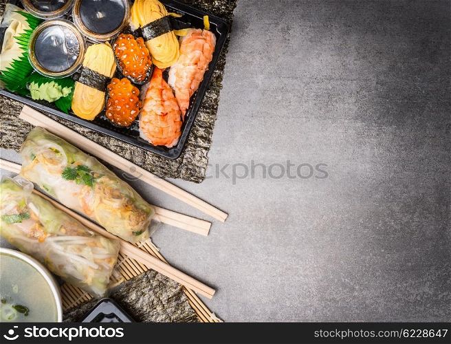 Sushi menu with summer rolls, nigiri and soy sauce on gray stone background, top view, place for text, border