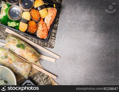 Sushi menu with summer rolls, nigiri and soy sauce on gray stone background, top view, place for text, border