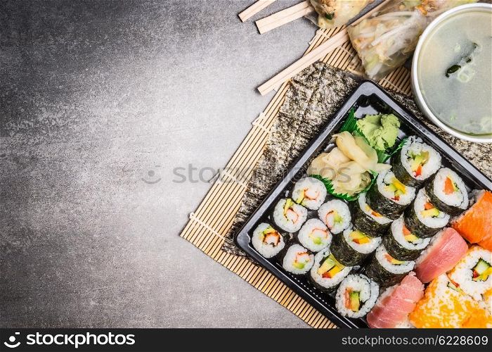 Sushi menu with summer rolls, nigiri , soy sauce and miso soup on gray stone background, top view, place for text, border