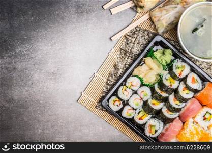 Sushi menu with summer rolls, nigiri , soy sauce and miso soup on gray stone background, top view, place for text, border