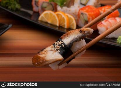 sushi on chopsticks close up on a background of sushi dishes. sushi on a black plate