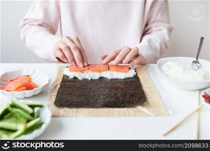 Sushi preparation process, the girl makes sushi with different flavors - fresh salmon, caviar, avocado, cucumber, ginger, rice. Sushi preparation process, the girl makes sushi with different flavors - fresh salmon, caviar, avocado, cucumber, ginger, rice.