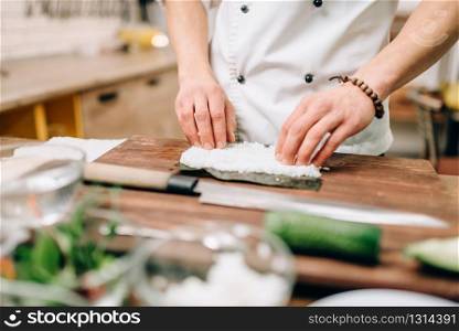 Sushi preparation process, traditional japanese food. Male cook making rolls on the kitchen. Sushi preparation process, japanese food