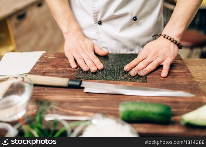 Sushi preparation, traditional japanese food. Male cook making rolls on the kitchen. Sushi preparation, traditional japanese food