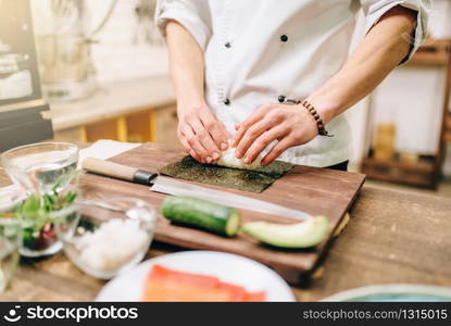 Sushi preparation, traditional japanese food. Male cook making rolls on the kitchen. Sushi preparation, traditional japanese food