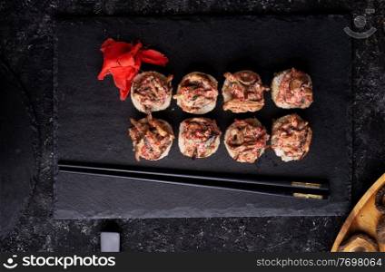 sushi roll  with shiitake mushrooms  served  at black dish  at black table. flat lay