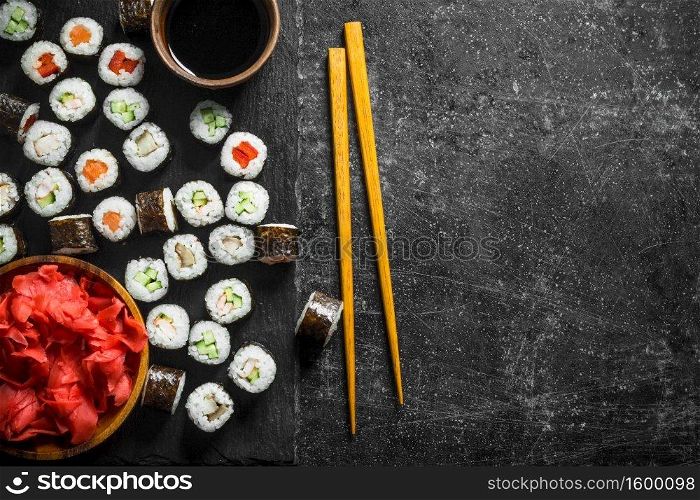 Sushi rolls on a stone Board with soy sauce and ginger. On dark rustic background. Sushi rolls on a stone Board with soy sauce and ginger.