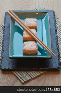 Sushi salmon parcels on dish with chopsticks
