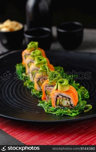 Sushi set of various products on a black stone plate. Blur background and selective focus
