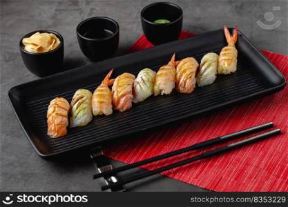 Sushi set of various products on a black stone plate. Blur background and selective focus