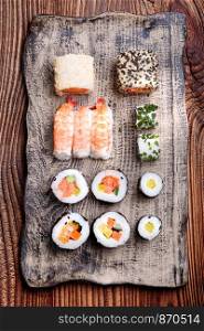 Sushi set on handmade pottery plate on wooden table from above