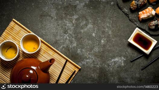 Sushi with soy sauce and fragrant tea. On the stone table. Sushi with soy sauce and fragrant tea.