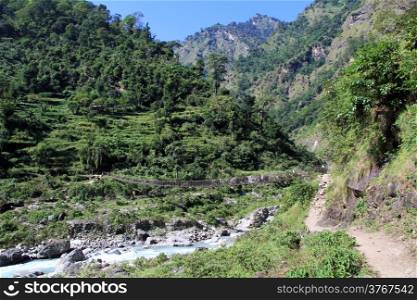 Suspension bridge and footpath near mountain river in Nepal