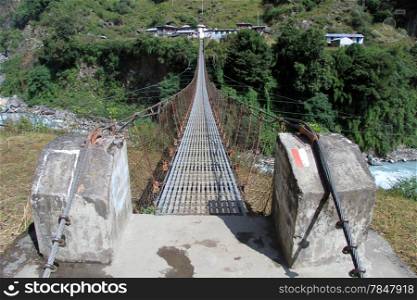 Suspension bridge and village near river in Nepal