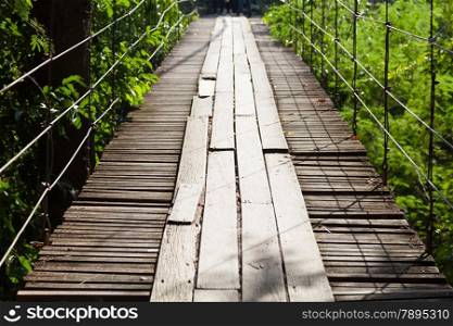 Suspension Bridge made of wood. Walking through the trees above a waterfall below.