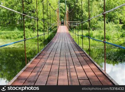 Suspension bridge over the river. Pedestrian suspension bridge over the river in the park