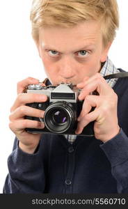 Suspicious teenage boy photographing through retro camera over white background