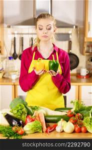 Suspicious young woman holding bell pepper vegetable thinking about meal or choosing good veggie.. Woman holding bell peppers paprika thinking