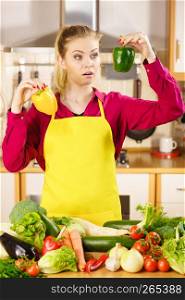 Suspicious young woman holding bell pepper vegetable thinking about meal or choosing good veggie.. Woman holding bell peppers paprika thinking