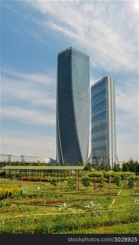 Sustainability concept of locally grown organic food in a modern downtown district with two glass skyscrapers and blue sky with copy space - captured in Milan, Lombardy, Italy.. Sustainability concept of locally grown organic food in a modern downtown district with two glass skyscrapers and blue sky with copy space - captured in Milan, Lombardy, Italy