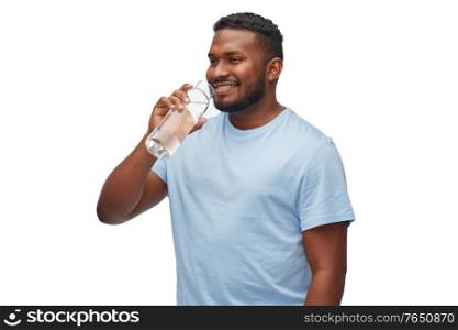 sustainability, consumerism and eco friendly concept - happy smiling african american man drinking water from reusable glass bottle over white background. happy african man drinking water from glass bottle