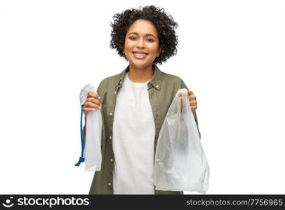 sustainability, eco living and people concept - portrait of happy smiling woman holding plastic and reusable string bag over white background. happy woman with plastic and reusable string bag