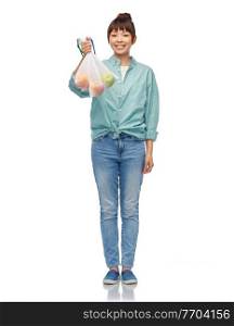 sustainability, eco living and people concept - portrait of happy smiling young asian woman in turquoise shirt and jeans holding reusable net bag with apples over white background. happy woman with apples in reusable net bag