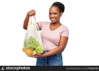 sustainability, food shopping and eco friendly concept - happy smiling african american woman holding reusable string bag with fruits and vegetables over white background. african woman with food in reusable string bag