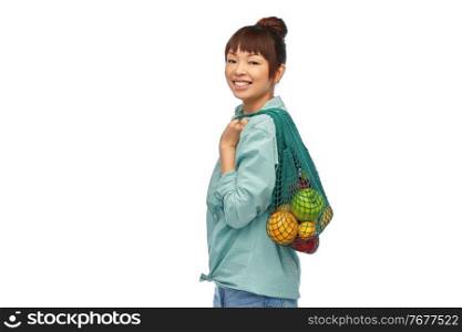sustainability, food shopping and eco friendly concept - happy smiling asian woman in turquoise shirt and jeans holding reusable string bag with fruits and vegetables over white background. happy asian woman with food in reusable string bag