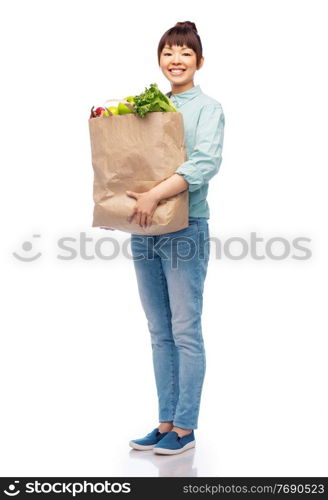 sustainability, food shopping and eco friendly concept - happy smiling asian woman in turquoise shirt and jeans holding paper bag with fruits and vegetables over white background. happy smiling asian woman with food in paper bag