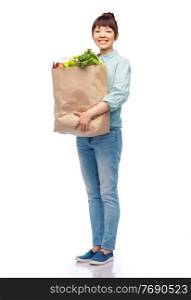 sustainability, food shopping and eco friendly concept - happy smiling asian woman in turquoise shirt and jeans holding paper bag with fruits and vegetables over white background. happy smiling asian woman with food in paper bag