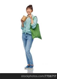 sustainability, food shopping and eco friendly concept - smiling asian woman in turquoise shirt and jeans holding reusable green tote bag eating takeaway wok with chopsticks over white background. asian woman with reusable bag for food and wok