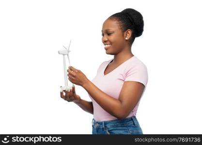 sustainable energy, power and people concept - happy smiling young african american woman with toy wind turbine over white background. happy african american woman with toy wind turbine