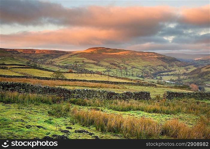 Swaledale in Yorkshire Dales National Park at sunrise with sun lighting hills