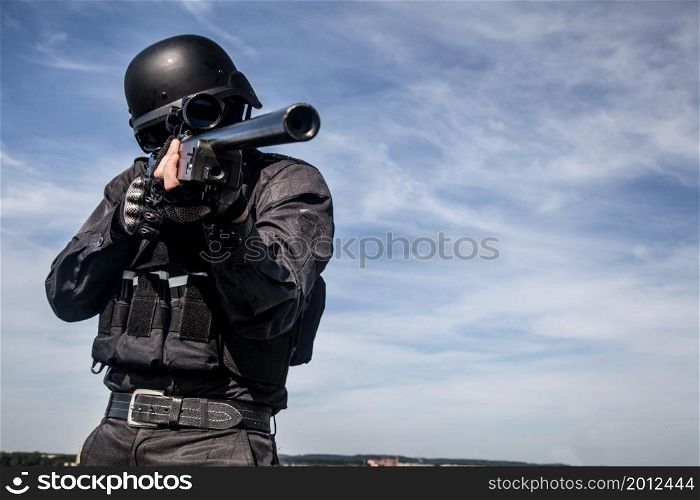 SWAT police sniper in black uniform in action. SWAT police sniper