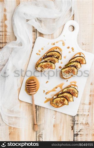 Swedish toasts with figs, cheese, rosemary, honey and walnuts on a cutting board. Top view
