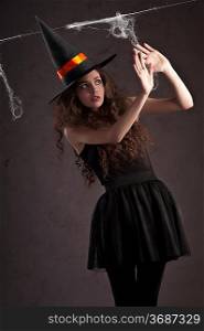 sweet and cute girl dressed as a witch with a huge black hat looking terrified
